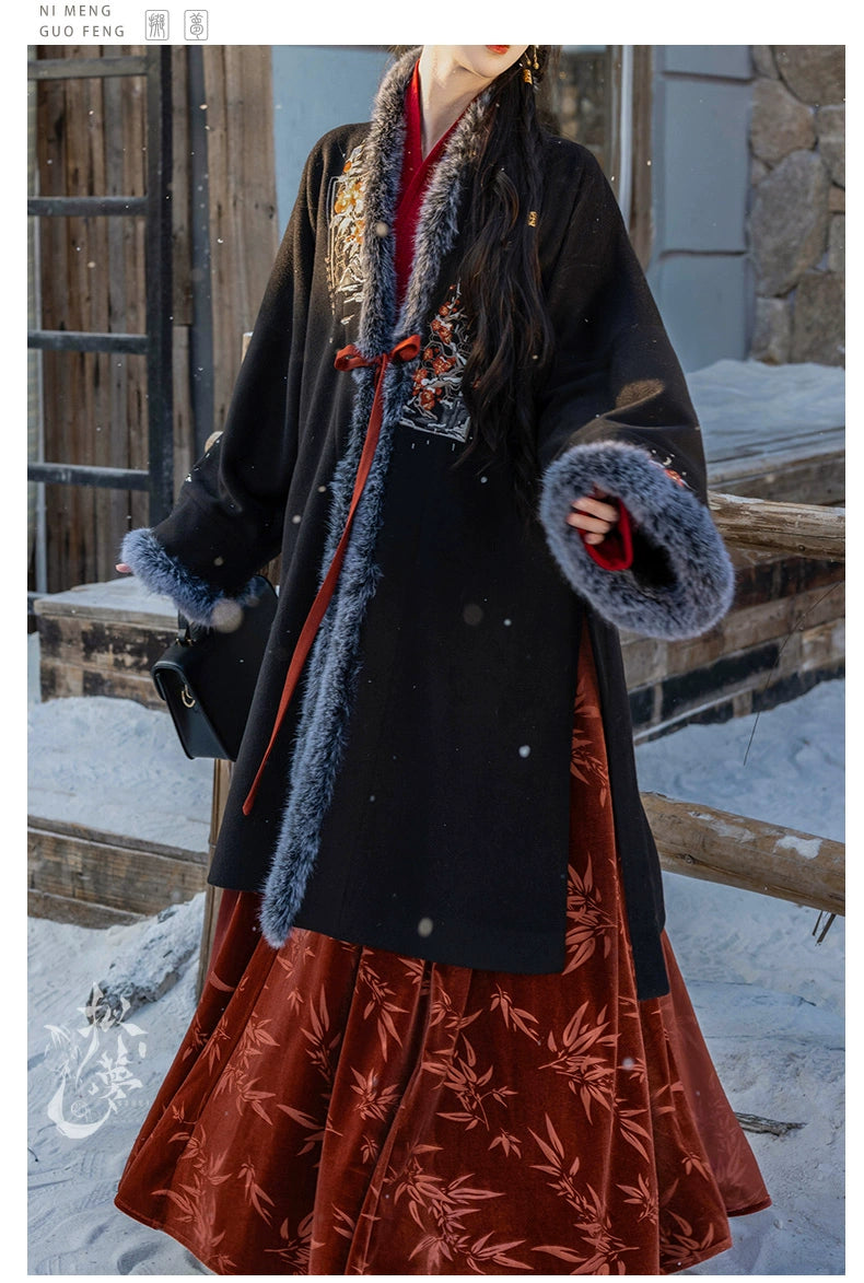 Black woolen Hanfu coat with floral embroidery and faux fur trim, styled with a red pleated skirt, perfect for snowy settings.