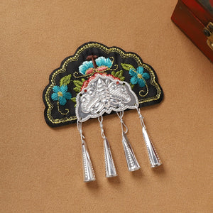 Black embroidered Guizhou Miao fridge magnet with silver cone fringe, handmade ethnic accessory for cultural home decor.