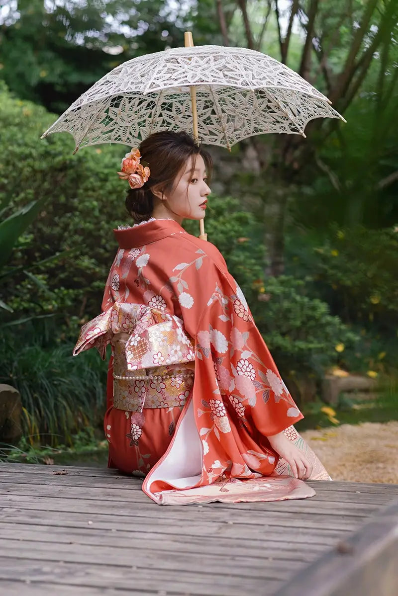 Back view of a Japanese orange kimono with chrysanthemum motifs, paired with a lace parasol, ideal for travel photography.