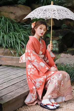 Japanese orange kimono with chrysanthemum patterns, styled with a lace parasol and floral hairpiece, perfect for travel photography.