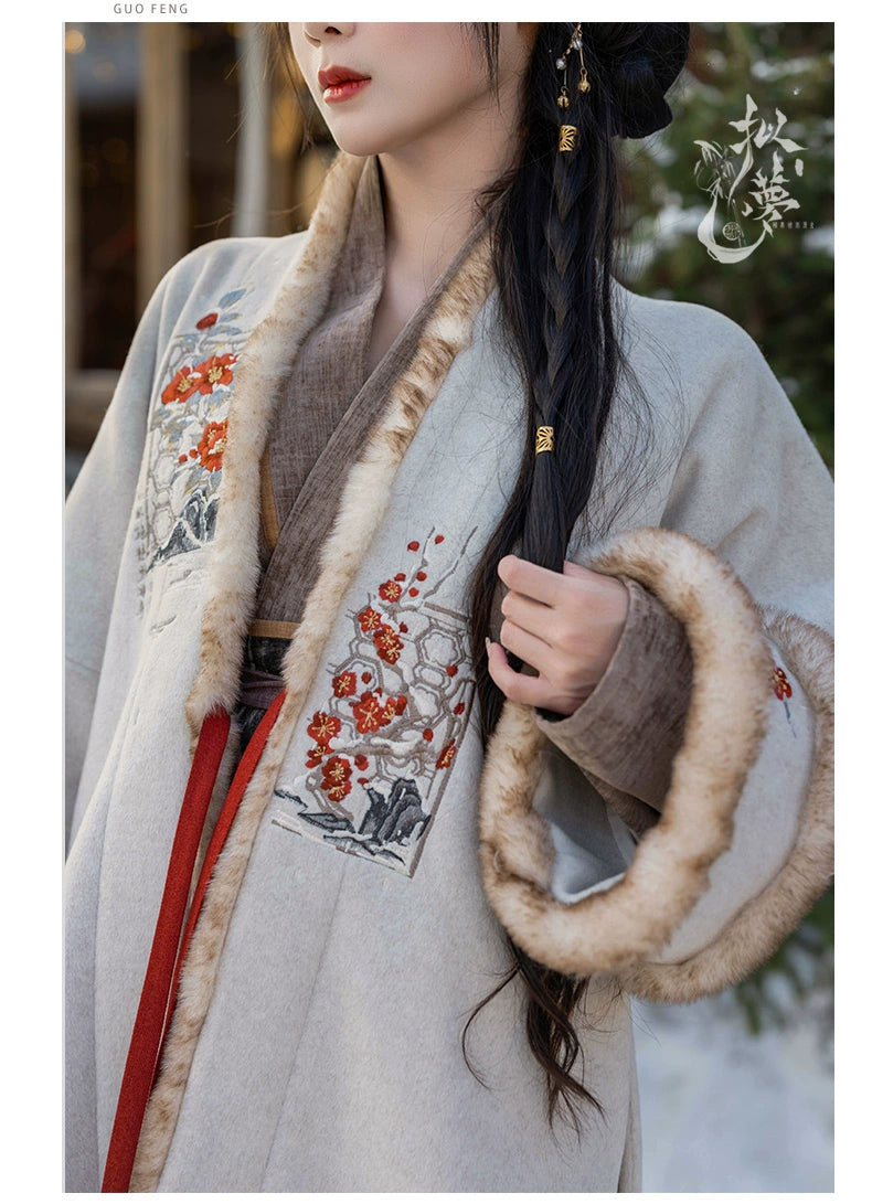 Close-up of white woolen Hanfu coat with intricate floral embroidery and plush faux fur cuffs, styled for traditional winter wear.