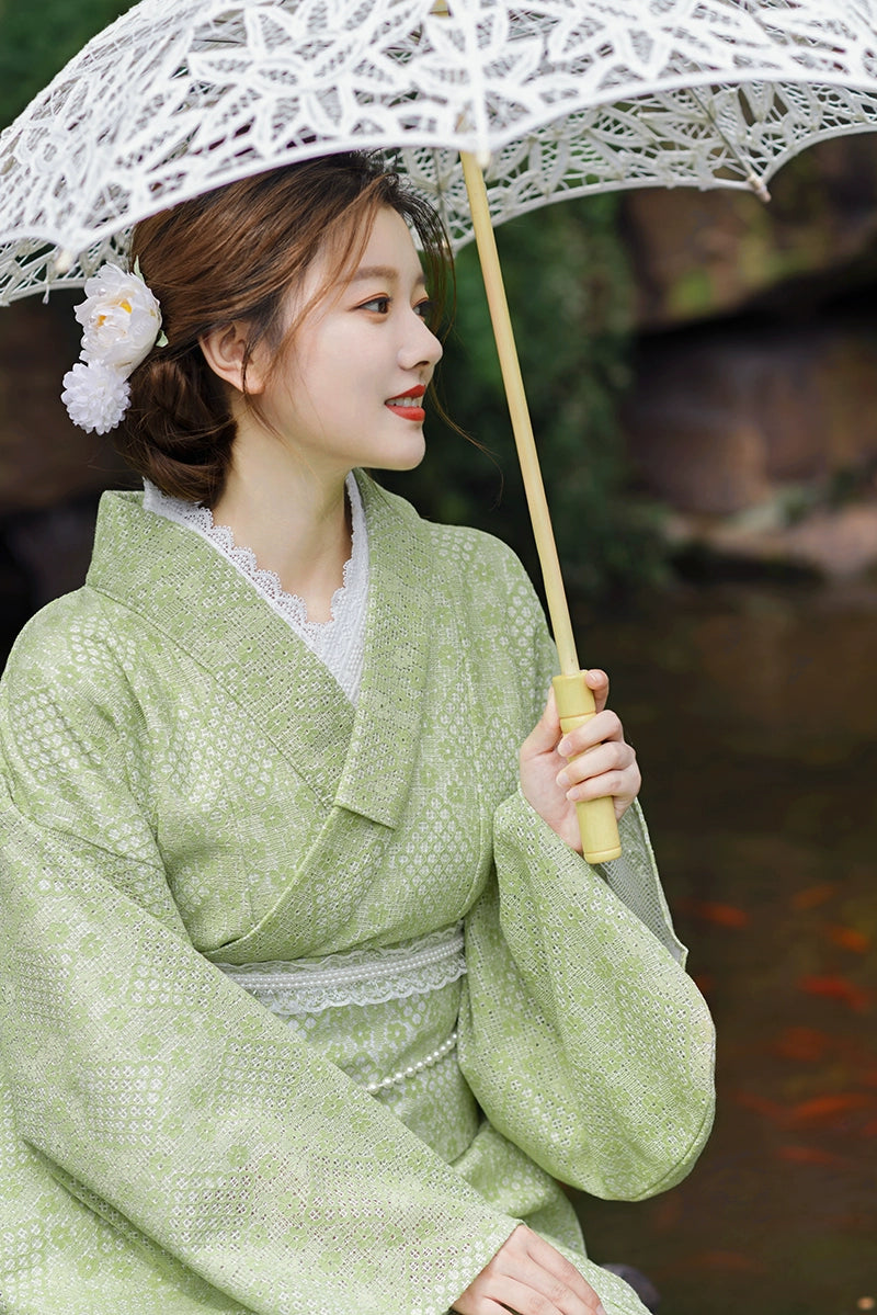 Close-up of model in green kimono dress holding lace parasol.