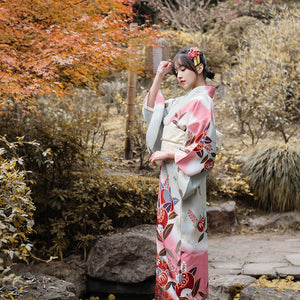 Elegant pink Japanese kimono yukata with floral patterns in a serene garden.