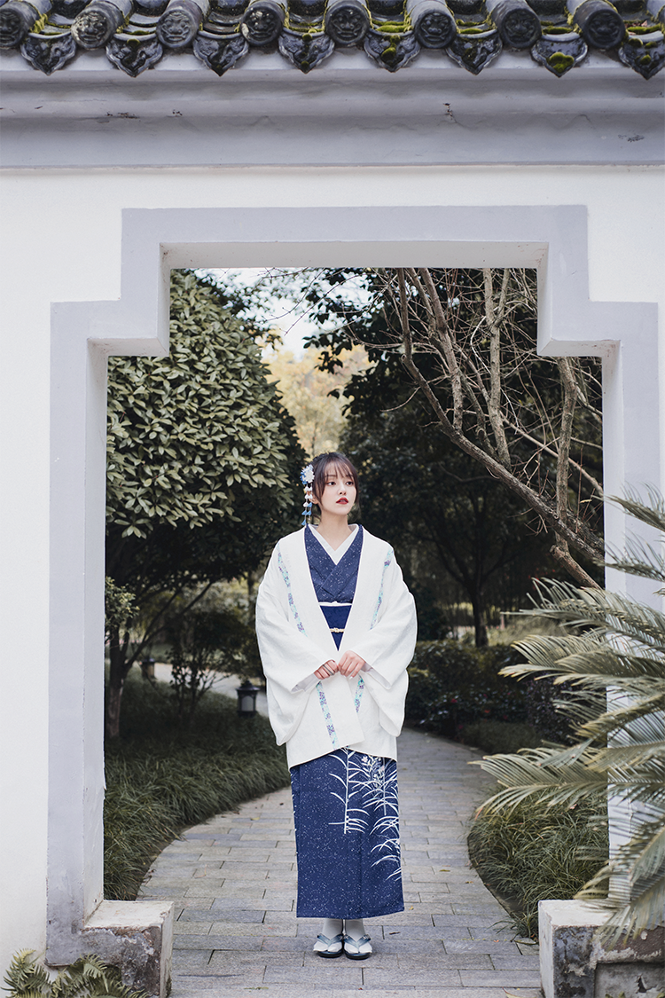 Blue Japanese kimono yukata paired with a white shawl in a garden setting.