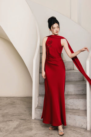 Red hand-beaded formal gown with flowing cape panel in staircase setting