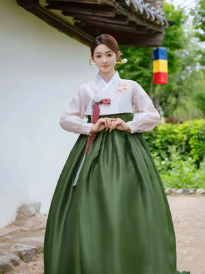 Graceful green Korean hanbok with pink ribbon, perfect for cultural events.