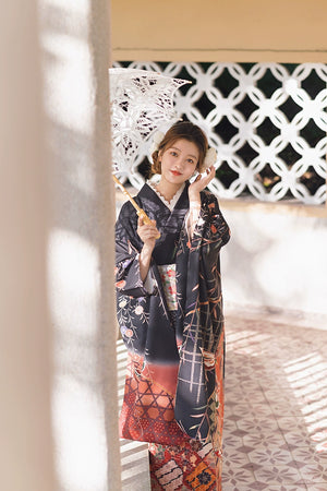 Model in a black butterfly kimono with floral details, holding a lace parasol.