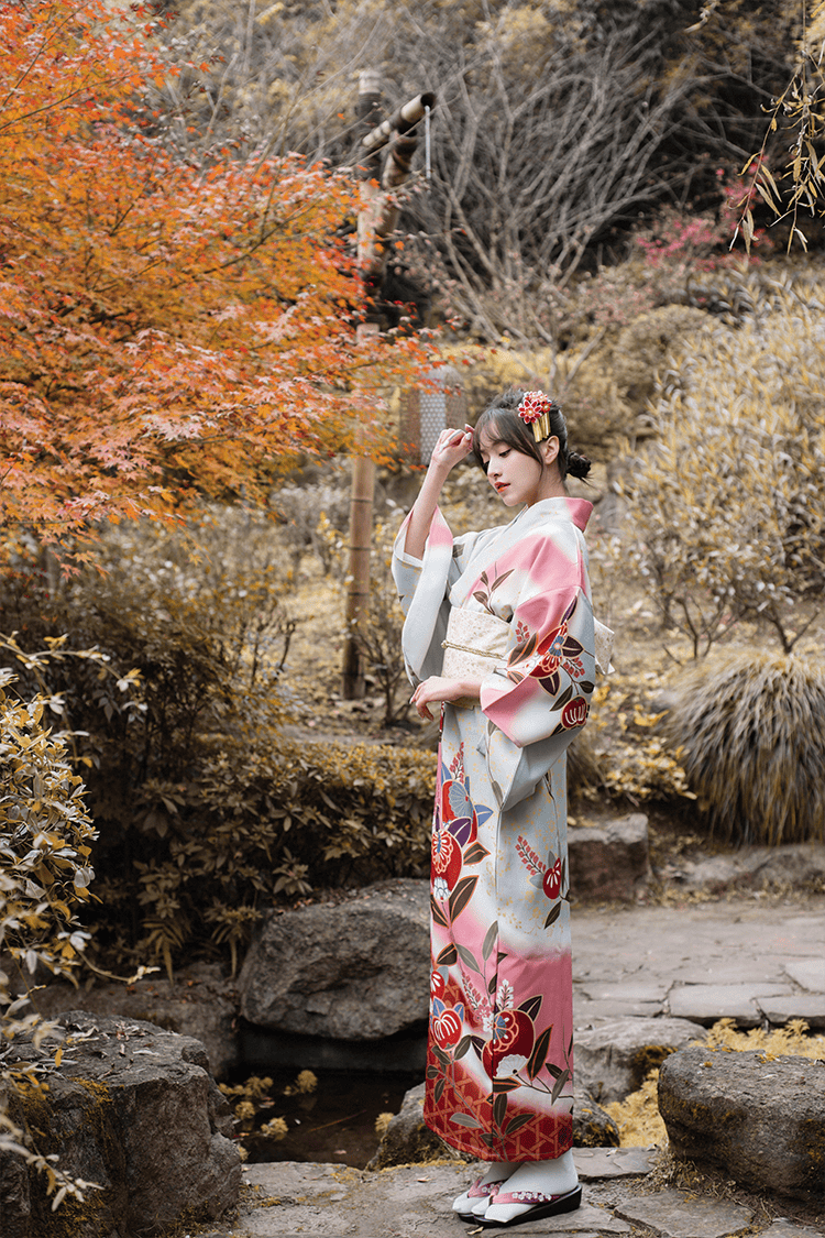 Elegant pink Japanese yukata with floral patterns, worn in a tranquil garden.