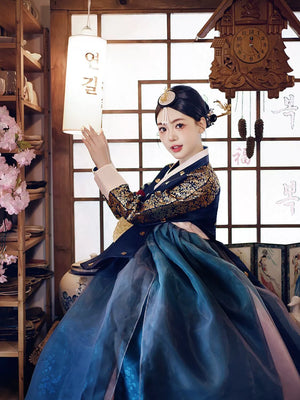 Woman in a navy blue bronzing hanbok court dress posing in a traditional Korean interior, blending heritage with timeless elegance.