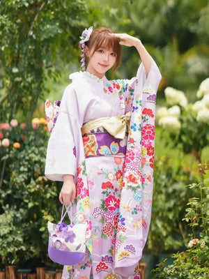 Women's Japanese traditional kimono with big sleeves, pastel floral patterns, and a purple obi, styled for cultural events or bar mitzvahs.