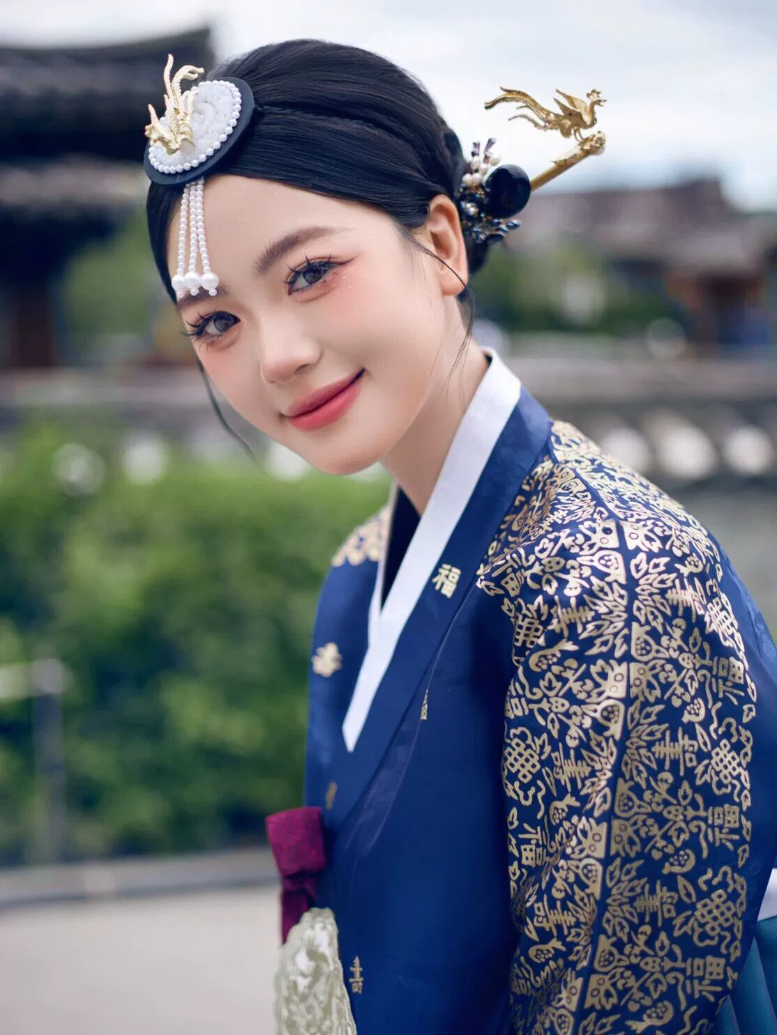 Close-up of a woman wearing a navy blue bronzing hanbok court dress with gold embroidery, highlighting intricate details and accessories.