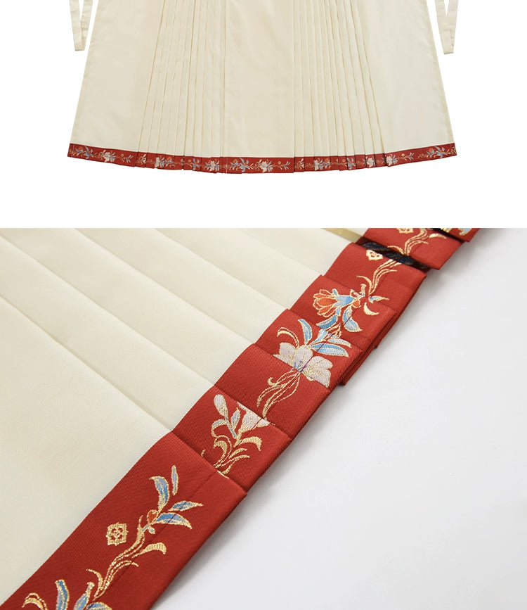 Close-up of cream pleated skirt with red embroidered hem, highlighting intricate details for engagement or banquet attire.