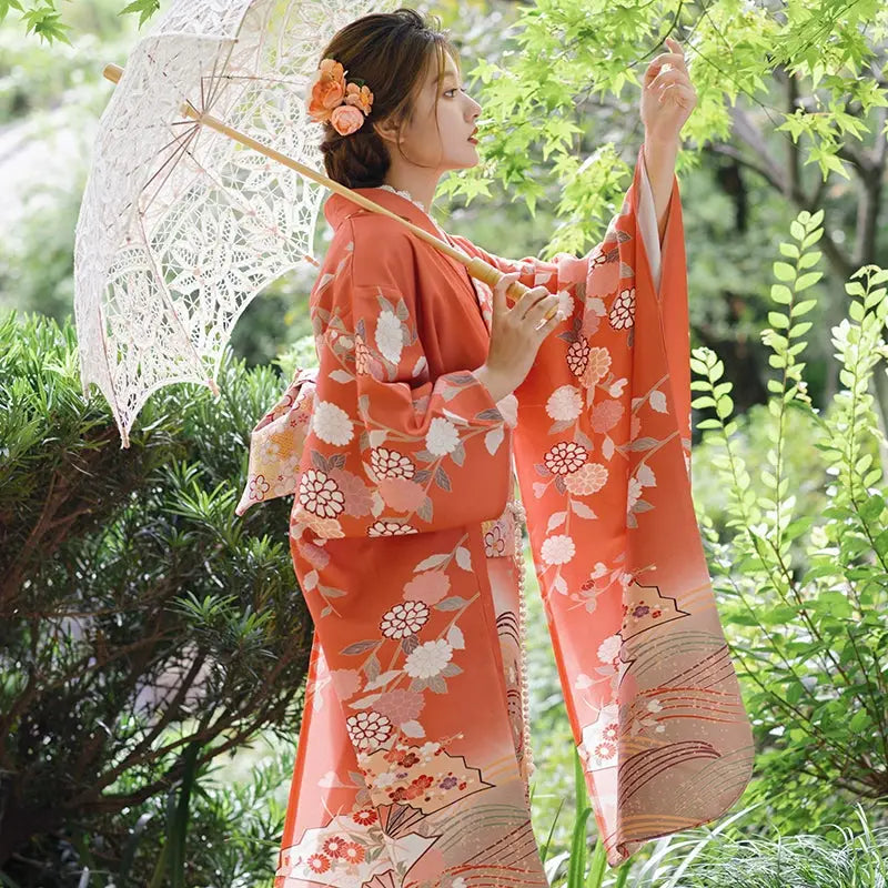 Side view of a retro orange kimono with chrysanthemum design, paired with a lace parasol, perfect for travel and photography.