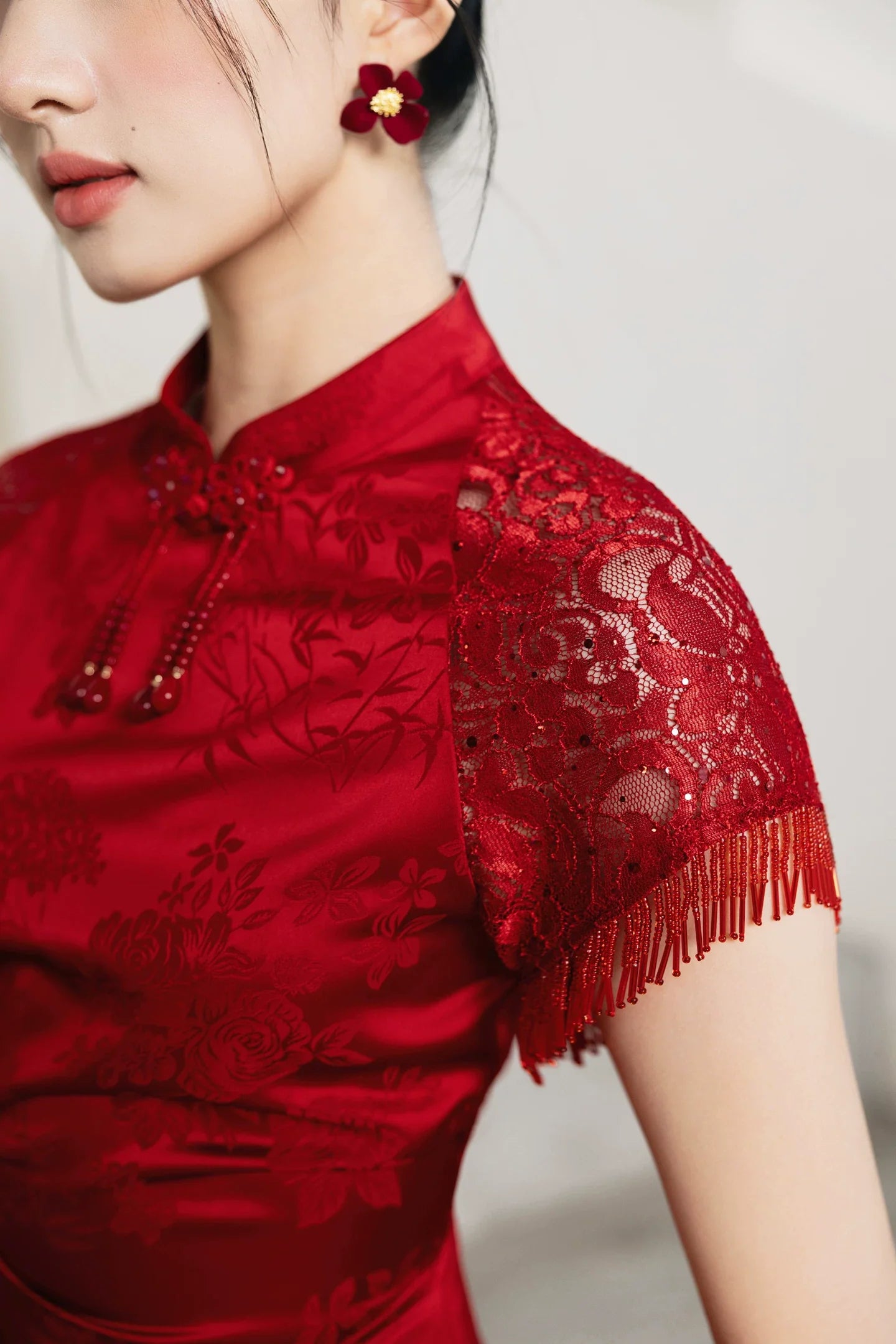 Close-up of red lace sleeve and mandarin collar on bridal cheongsam