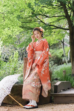 Japanese orange kimono with chrysanthemum patterns, styled with floral hair accessories and a lace parasol for travel photography.