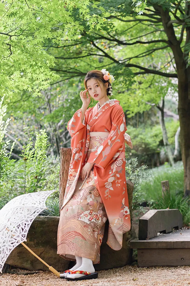 Japanese orange kimono with chrysanthemum patterns, styled with floral hair accessories and a lace parasol for travel photography.