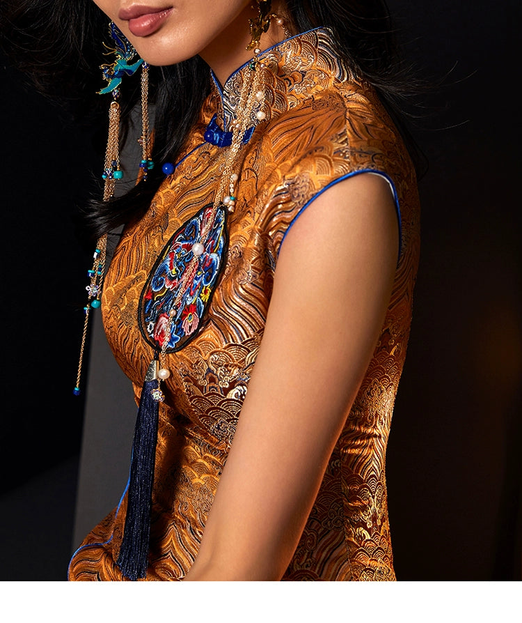 Close-up of orange cheongsam with Ukiyo-e inspired embroidery and tassel detail.