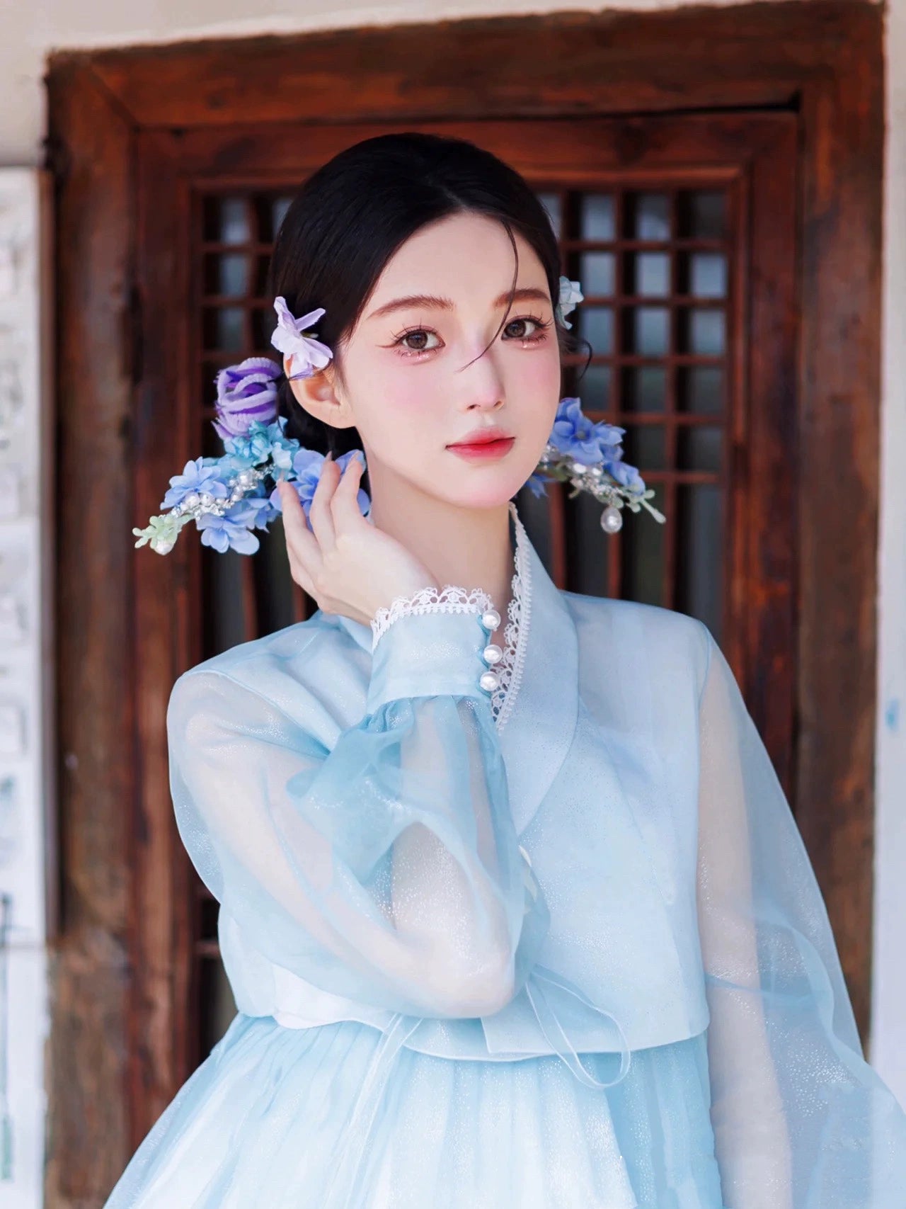 Blue Hanbok dress with intricate details, worn with floral hair accessories.