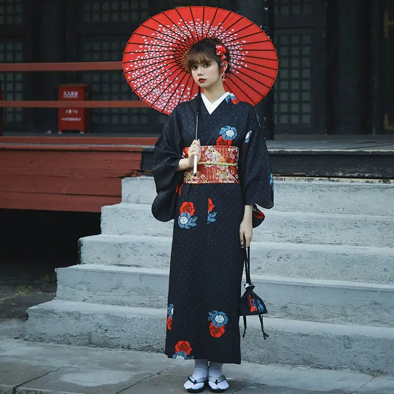 Elegant Japanese yukata in black with red and blue floral patterns, paired with a red umbrella. Perfect for Halloween or formal occasions.