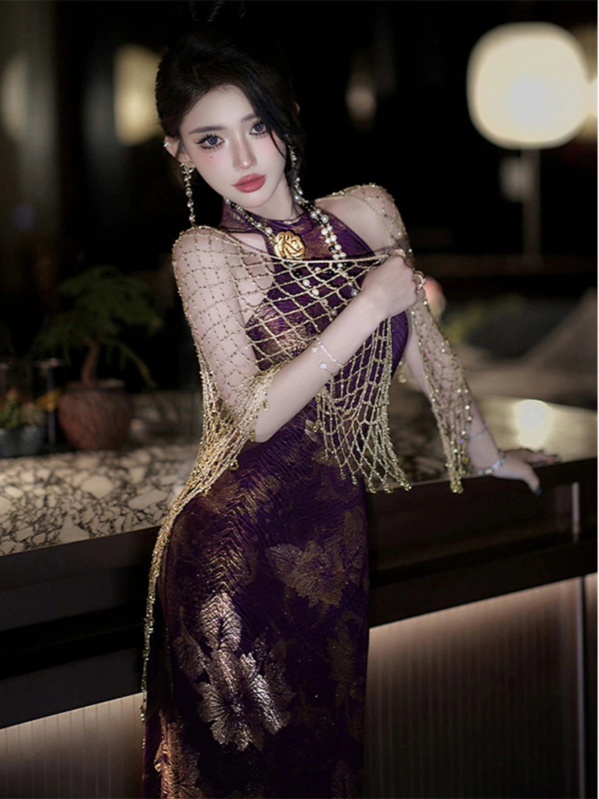 Close-up of purple jacquard cheongsam dress with gold floral details, paired with a shimmering gold shawl for a sophisticated style.