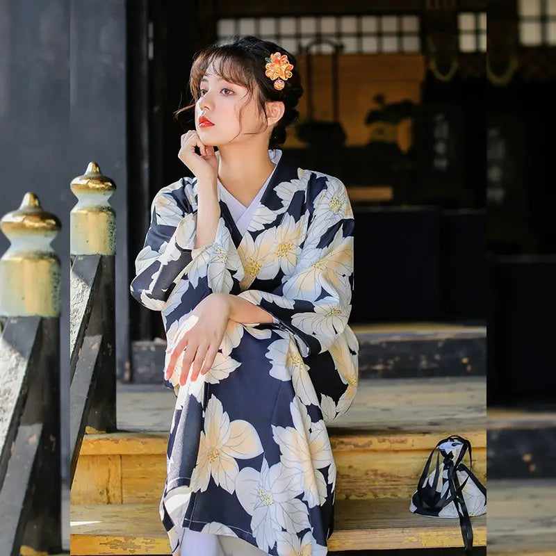 Woman seated in a black and white floral Japanese kimono dress, showcasing its elegant design and traditional craftsmanship.