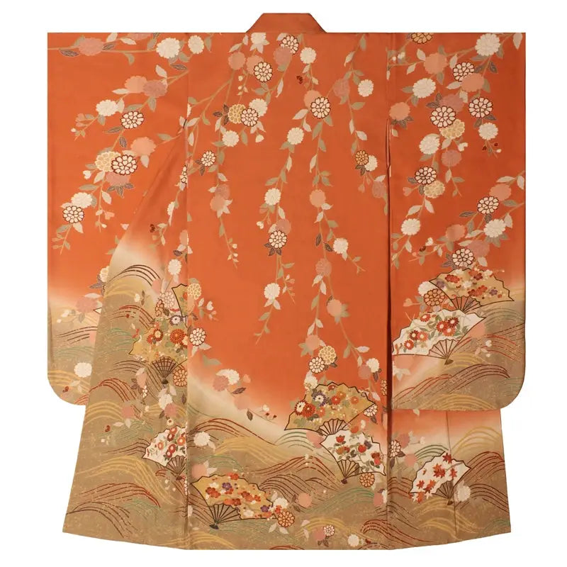 Flat-lay of an orange kimono featuring chrysanthemum patterns and intricate detailing, showcasing its retro Japanese design.