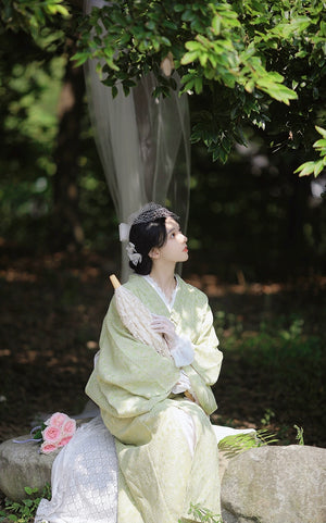 Model gazing upward in green retro kimono with lace parasol.