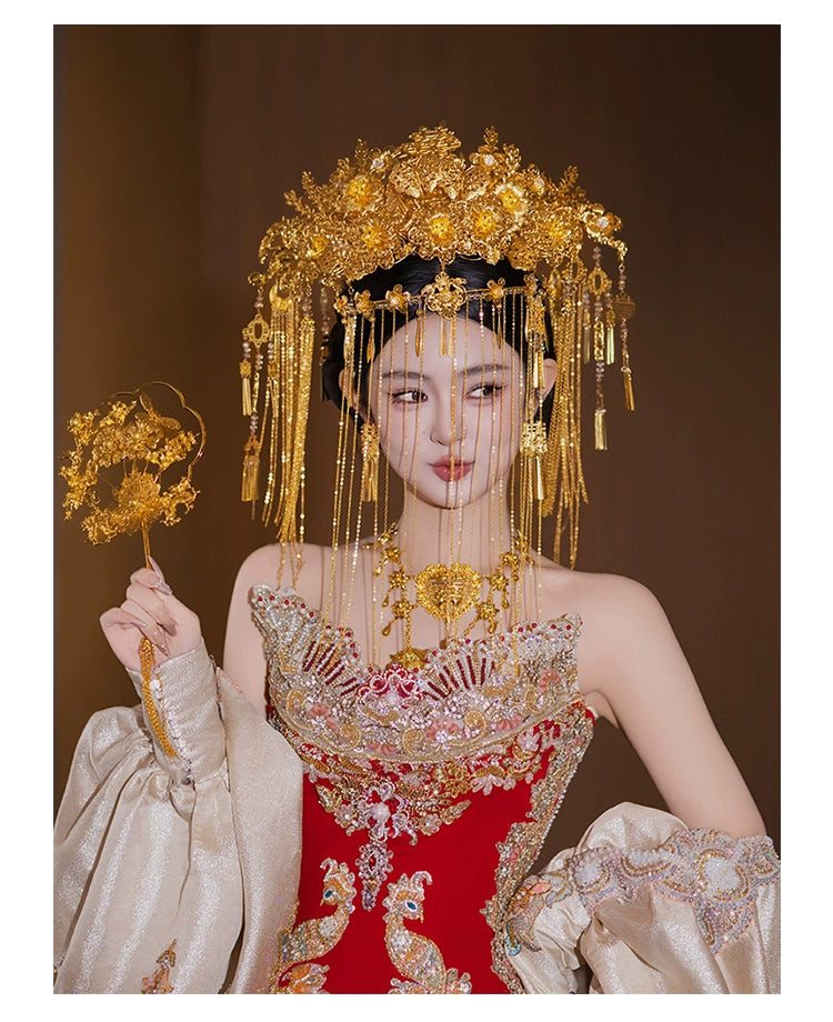 Bride in red and gold attire holding floral fan, wearing golden curtain headdress for Chinese wedding hair accessory styling.