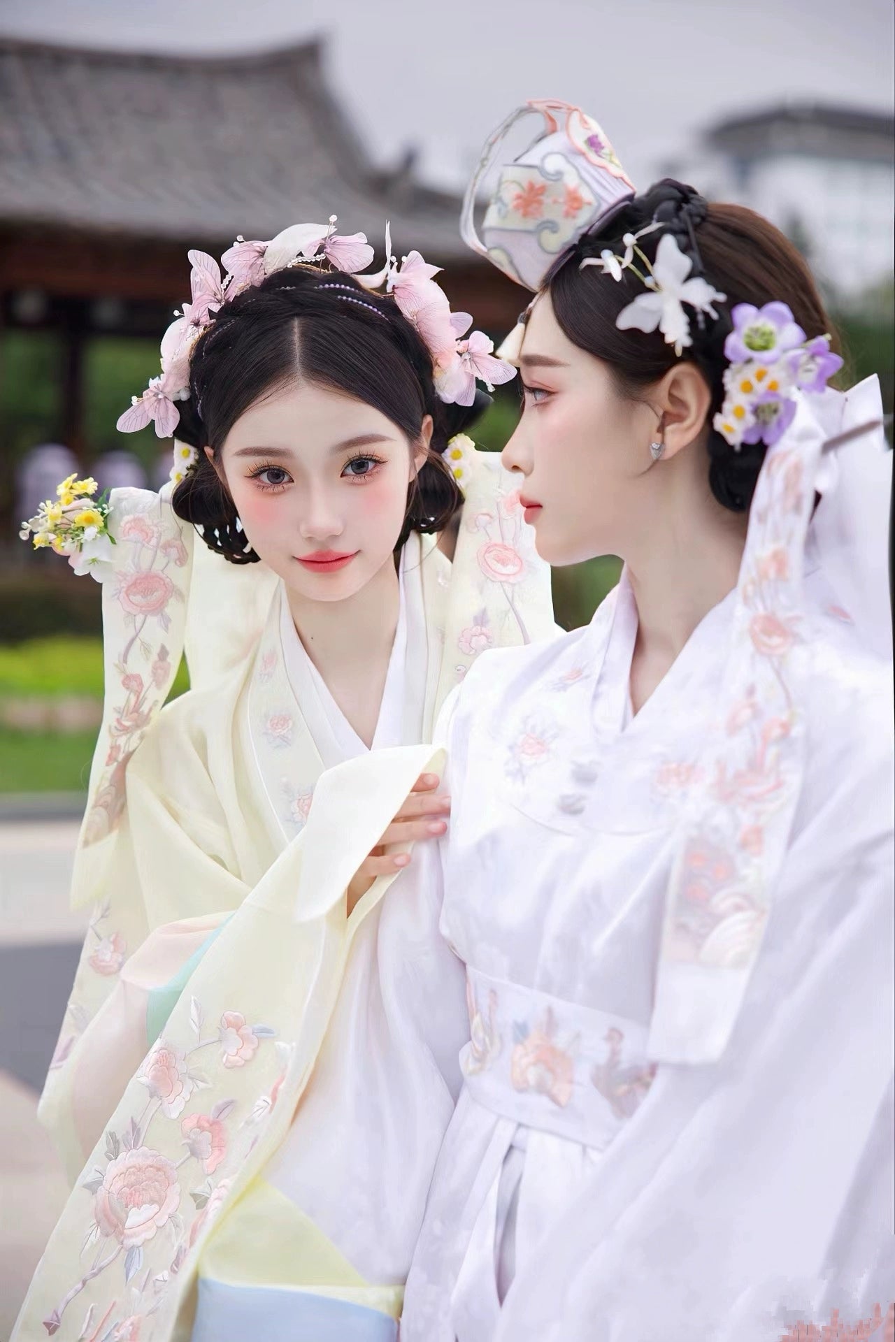 Close-up of two brides in Muzhi Korean embroidered wedding dresses, showcasing delicate floral embroidery and pastel hues for a sophisticated wedding.