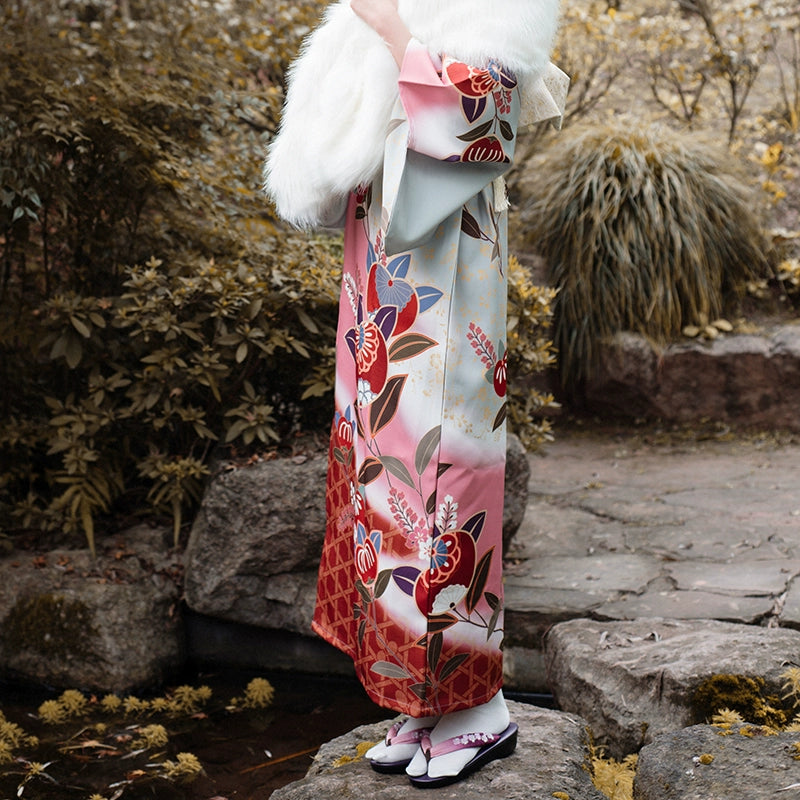 Close-up of pink Japanese kimono with intricate floral designs and white fur shawl.