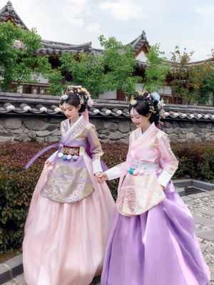 Two women walking in pink and purple Hanbok, showcasing traditional Korean elegance.