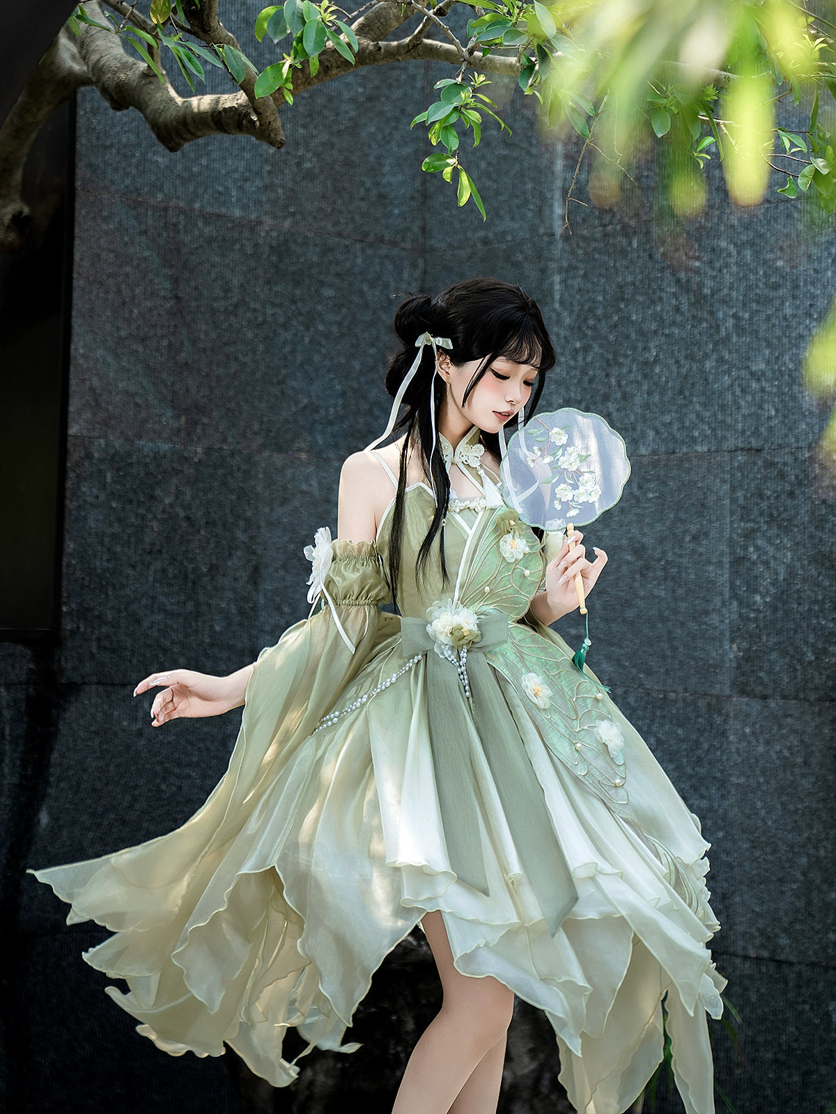 Model in Flower Marriage Green Lolita Dress holding a fan, showcasing the dress’s flowing design and floral embellishments.