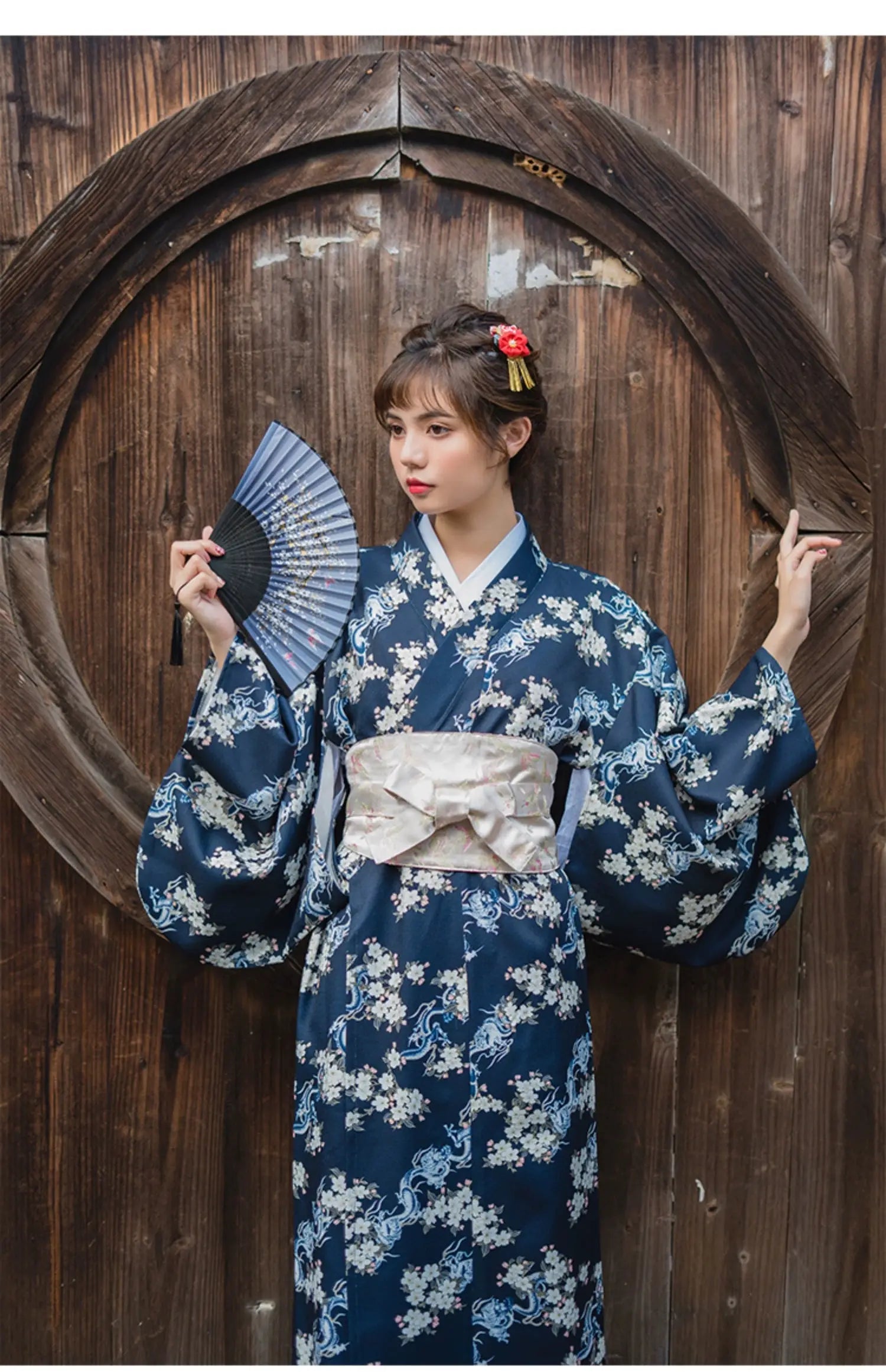 Traditional Japanese yukata in blue floral design, styled with a white brocade kimono belt seal, worn by a woman holding a fan.