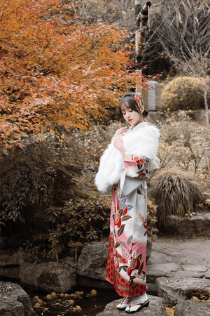 Pink floral kimono with white fur shawl, styled in a serene autumn garden.