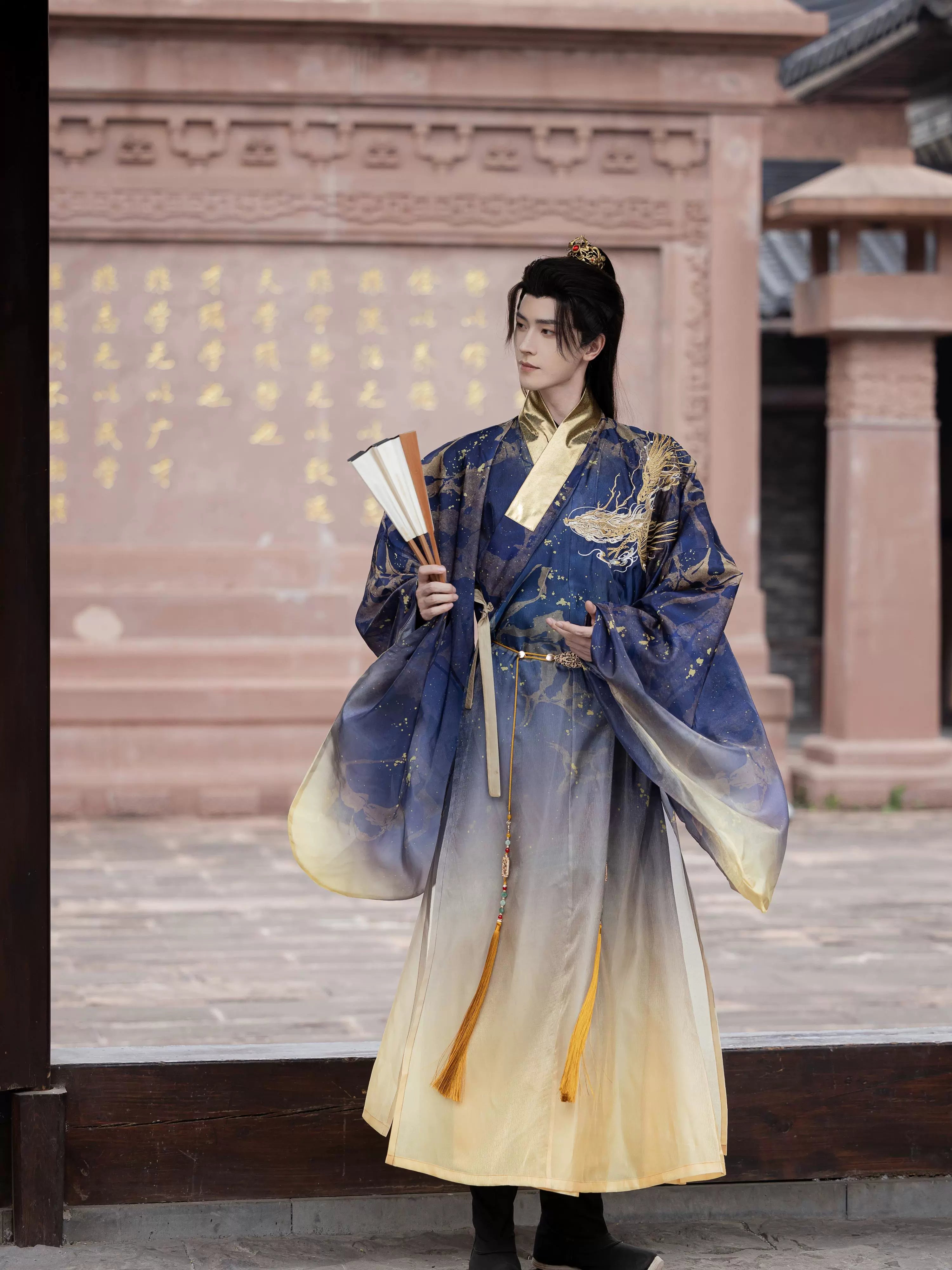 Hanfu Printing Smudge Daoist Robe in Ming blue with golden embroidery, styled with a fan and tassel belt for a refined traditional look.