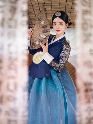 Graceful woman in a navy blue bronzing hanbok court dress holding a decorative fan, showcasing traditional Korean elegance and style.