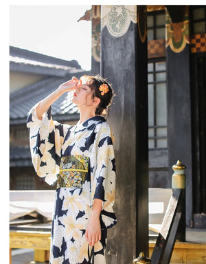 Full-length view of a Japanese kimono dress with a black and white floral pattern, styled for festivals with a decorative obi belt.