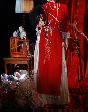 Red cheongsam dress with floral embroidery and tassel details, styled with a fan and pearl accessories for autumn and winter events.