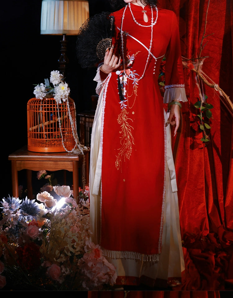 Red cheongsam dress with floral embroidery and tassel details, styled with a fan and pearl accessories for autumn and winter events.