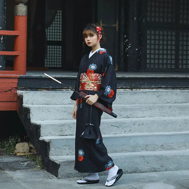 Black Japanese yukata with red floral obi belt, accessorized with a sword and traditional footwear. Ideal for literary and festive events.