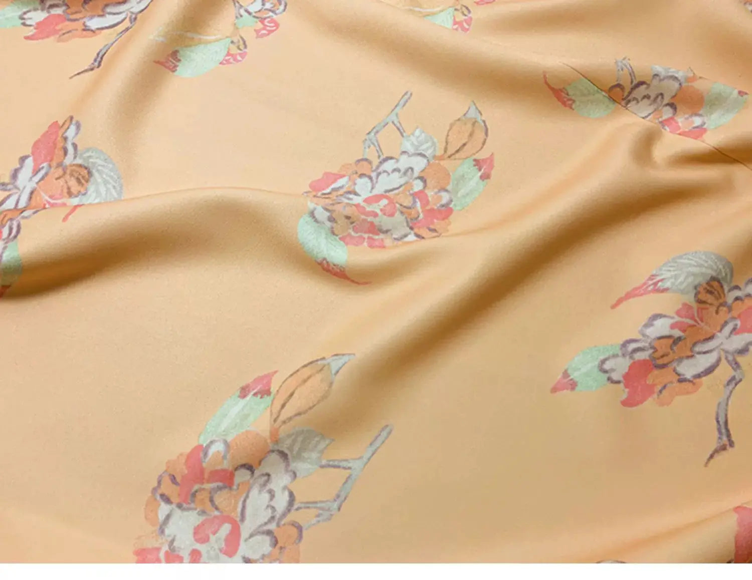 Close-up of the orange Japanese kimono-style yukata fabric, showcasing floral patterns in soft pastel tones.