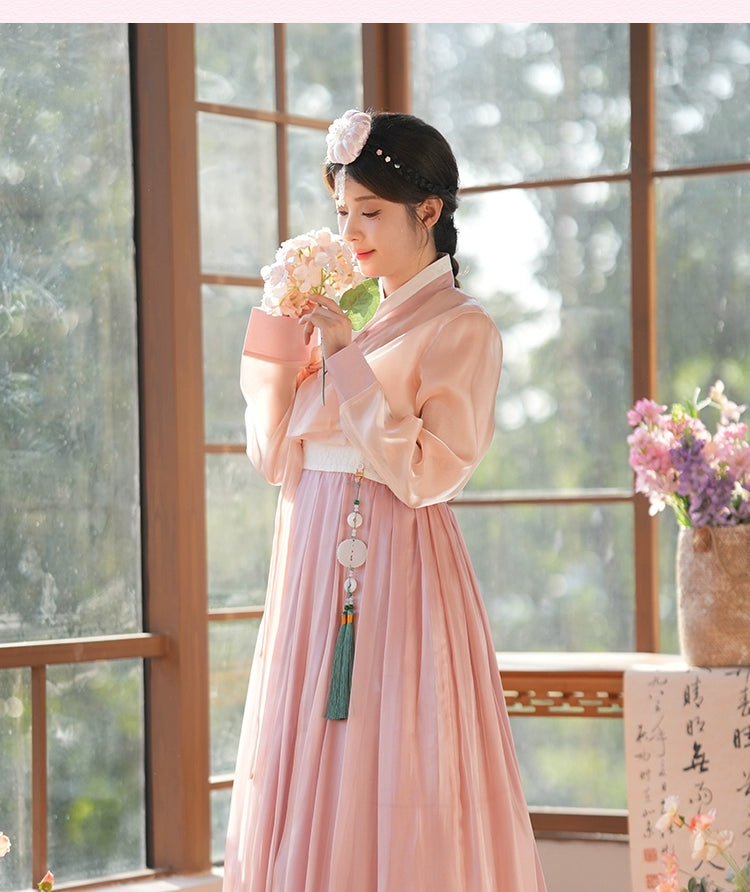 Traditional Korean hanbok dress in a delicate pink shade, styled with a floral hairpiece. A graceful and timeless ensemble.