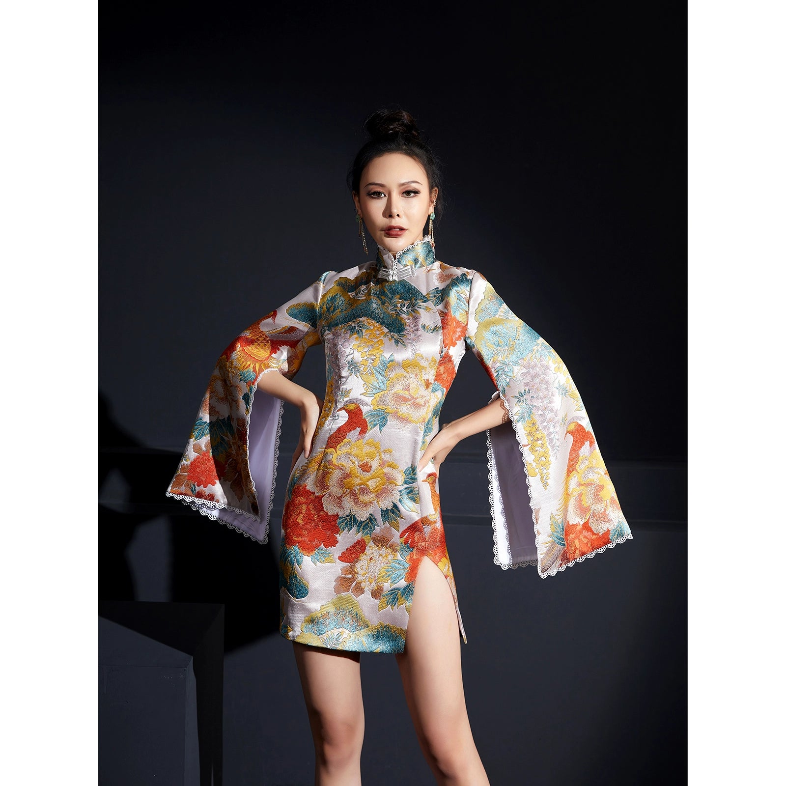 Model wearing white phoenix cheongsam with disc buckle and vibrant floral print.