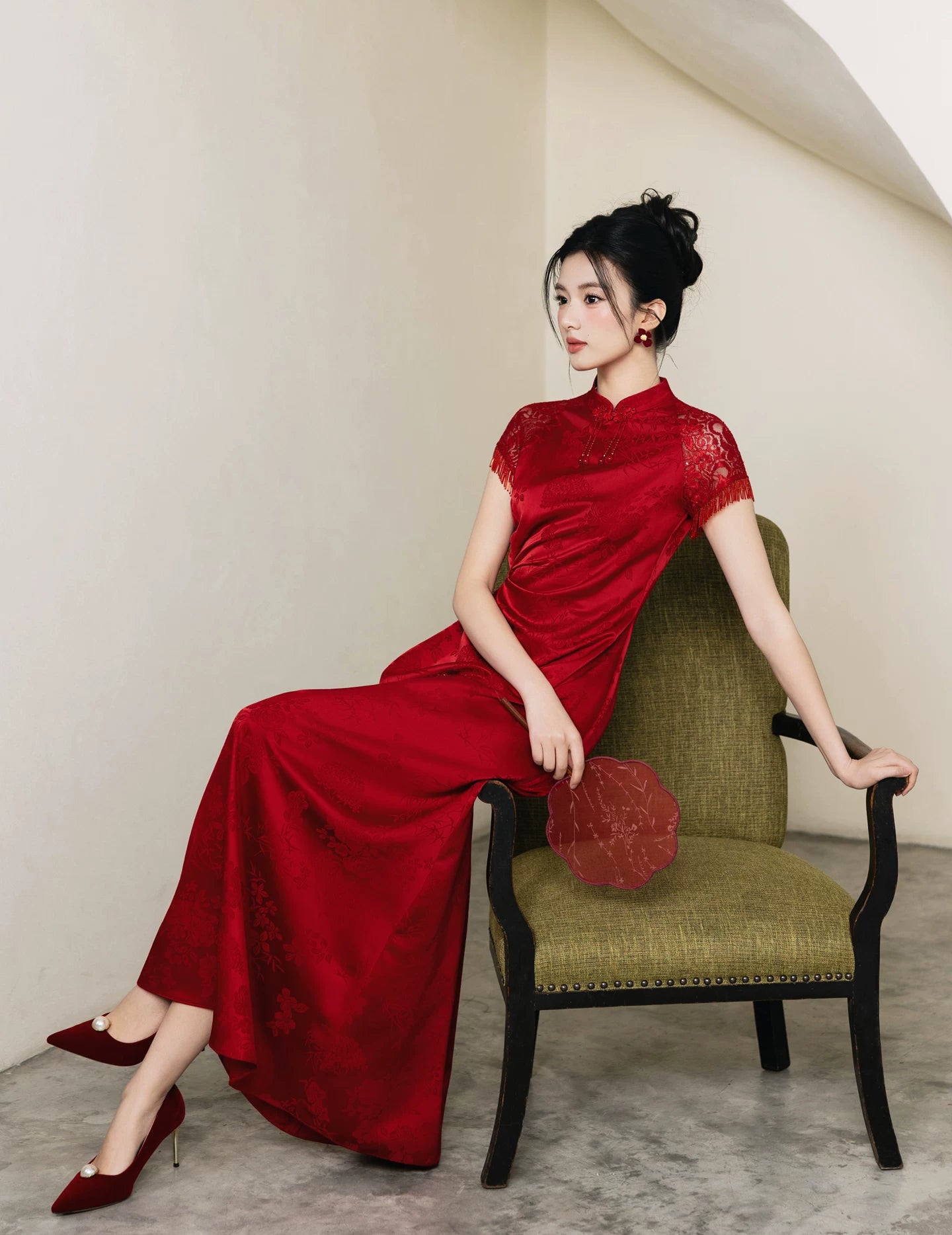 Seated side view of red A-line cheongsam wedding gown