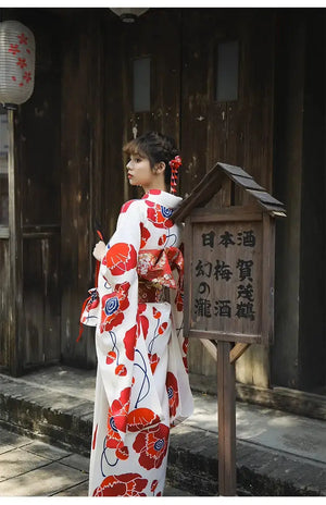 Back view of a white and red floral Japanese kimono dress, showcasing the detailed obi belt and traditional styling in an outdoor setting.