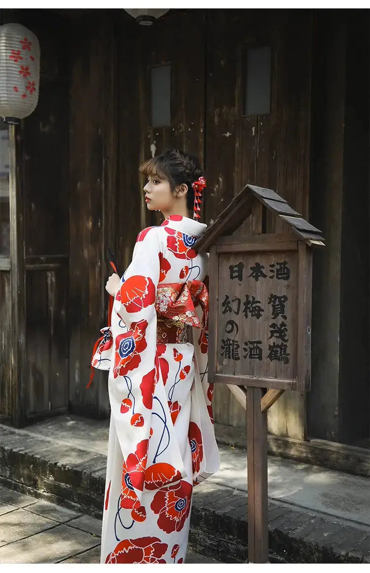 Back view of a white and red floral Japanese kimono dress, showcasing the detailed obi belt and traditional styling in an outdoor setting.