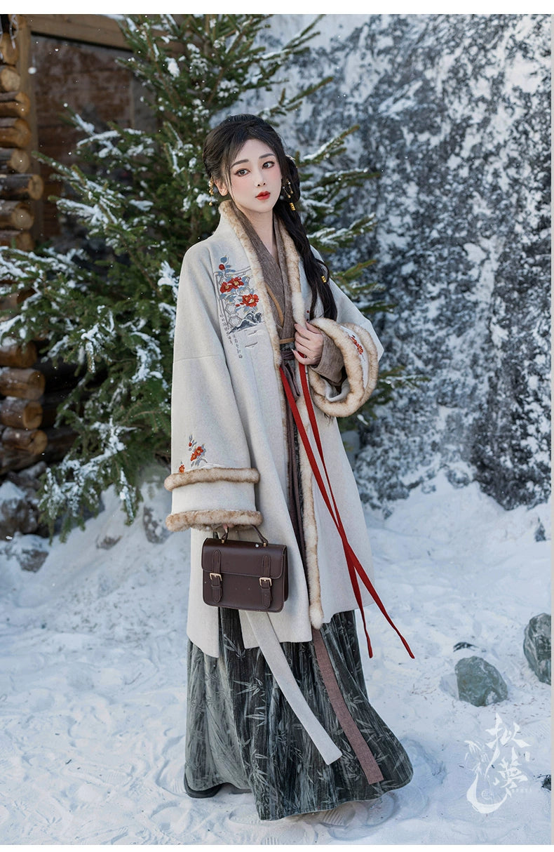 White woolen Hanfu coat with floral embroidery and faux fur trim, styled with a green pleated skirt, perfect for snowy settings.