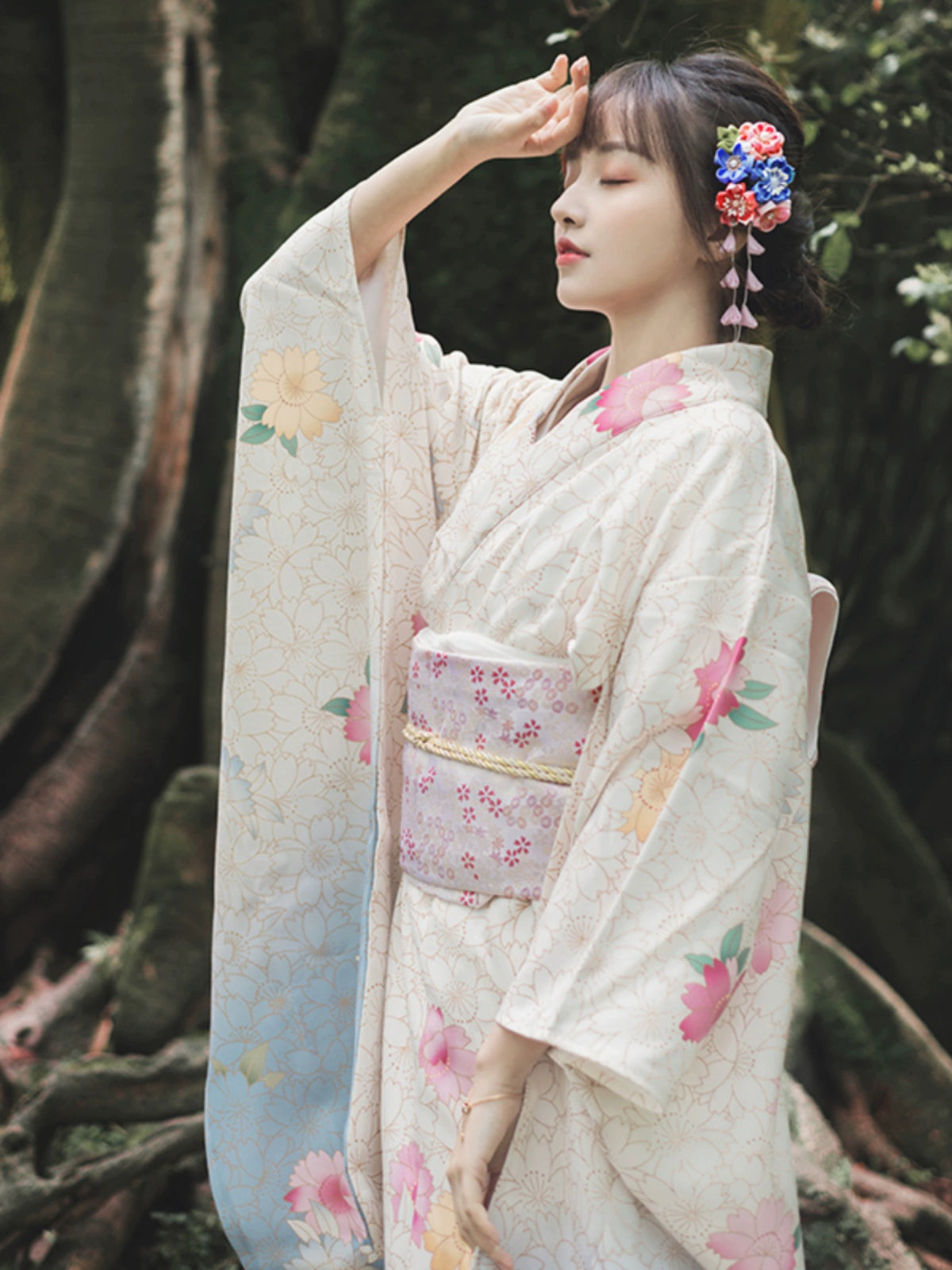 Graceful woman in a white floral kimono, posing in a natural outdoor setting.