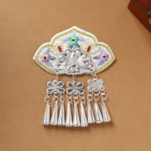 White embroidered Guizhou Miao fridge magnet with silver cone-shaped fringe, handmade ethnic decor for refrigerators.