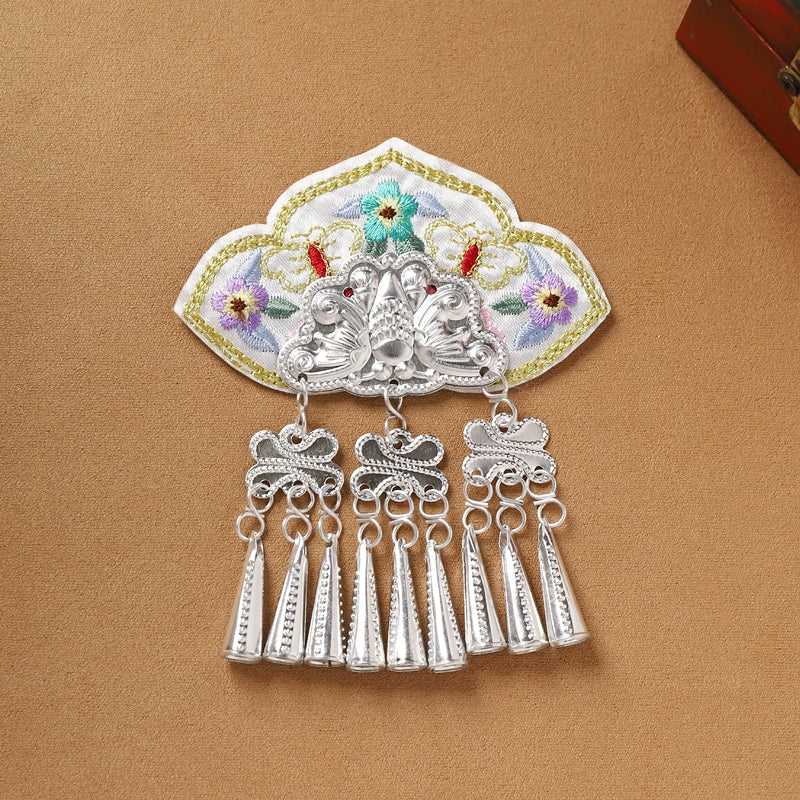 White embroidered Guizhou Miao fridge magnet with silver cone-shaped fringe, handmade ethnic decor for refrigerators.
